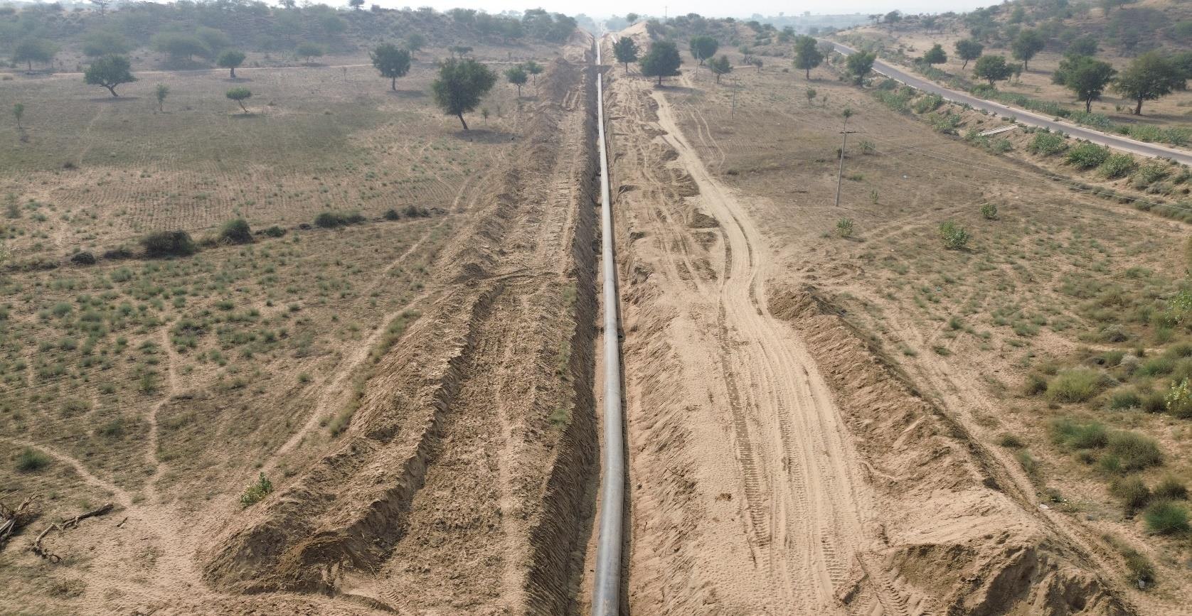 Aerial view of buried pipeline route through green desert fields