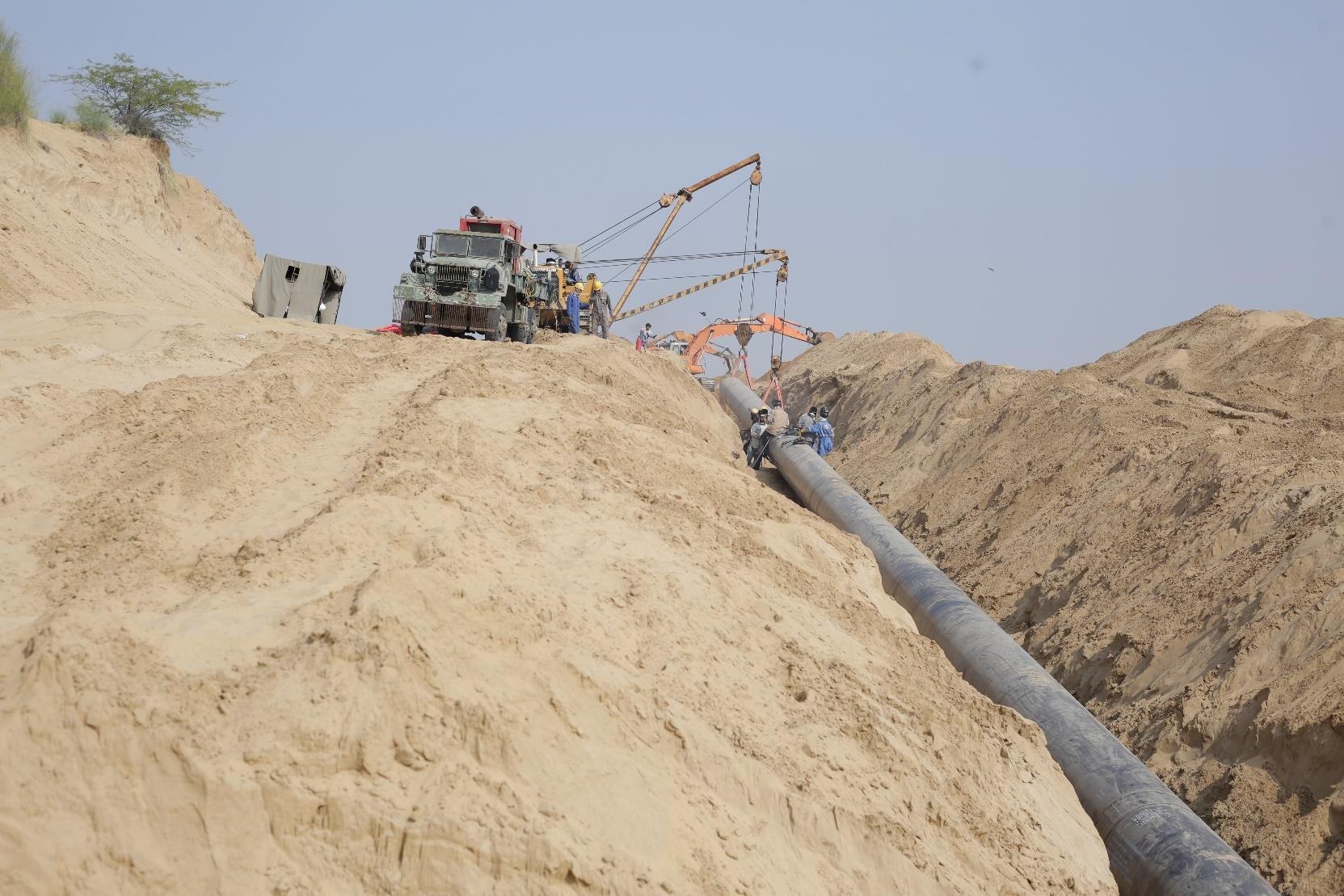 Heavy transport truck and crane positioning pipeline sections on site